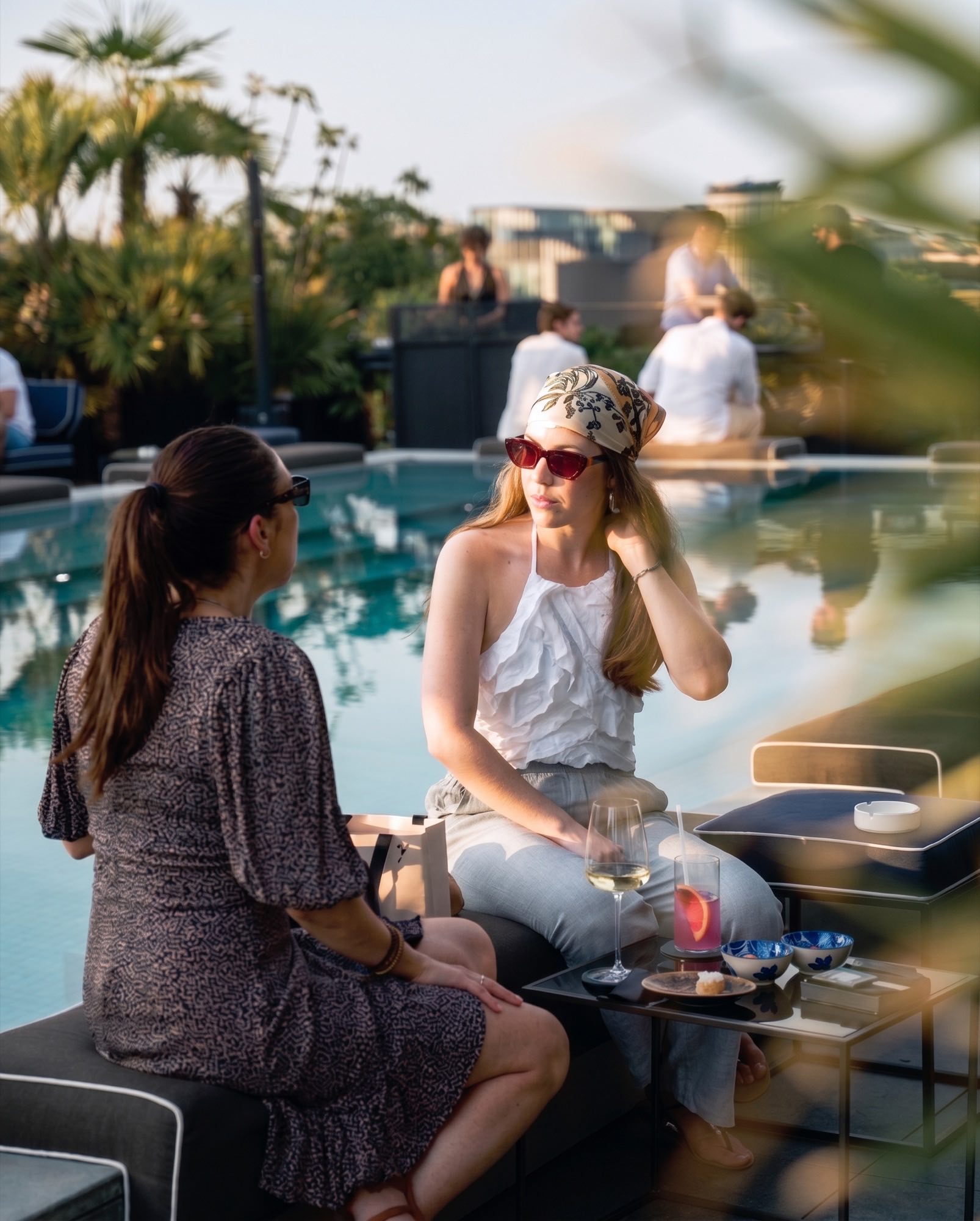 Due amiche sedute a bordo piscina al tramonto